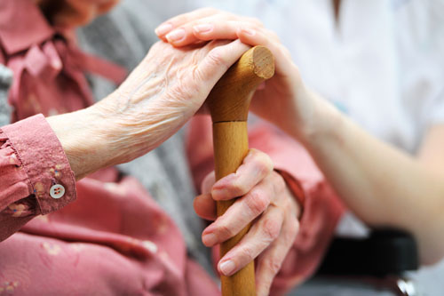 A nurse rests her hand on an elderly woman's hand