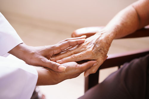 Nurse holds an elderly adult's hand
