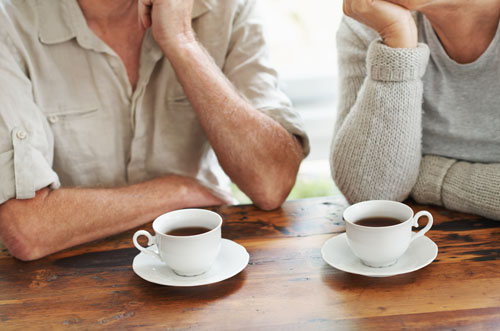 An elderly couple relax with two full teacups