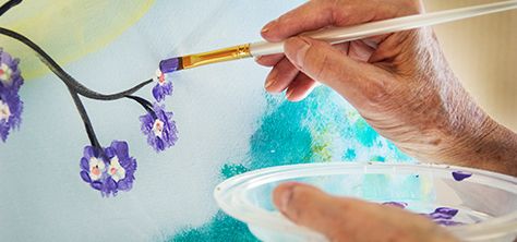 Elderly woman paints purple flowers