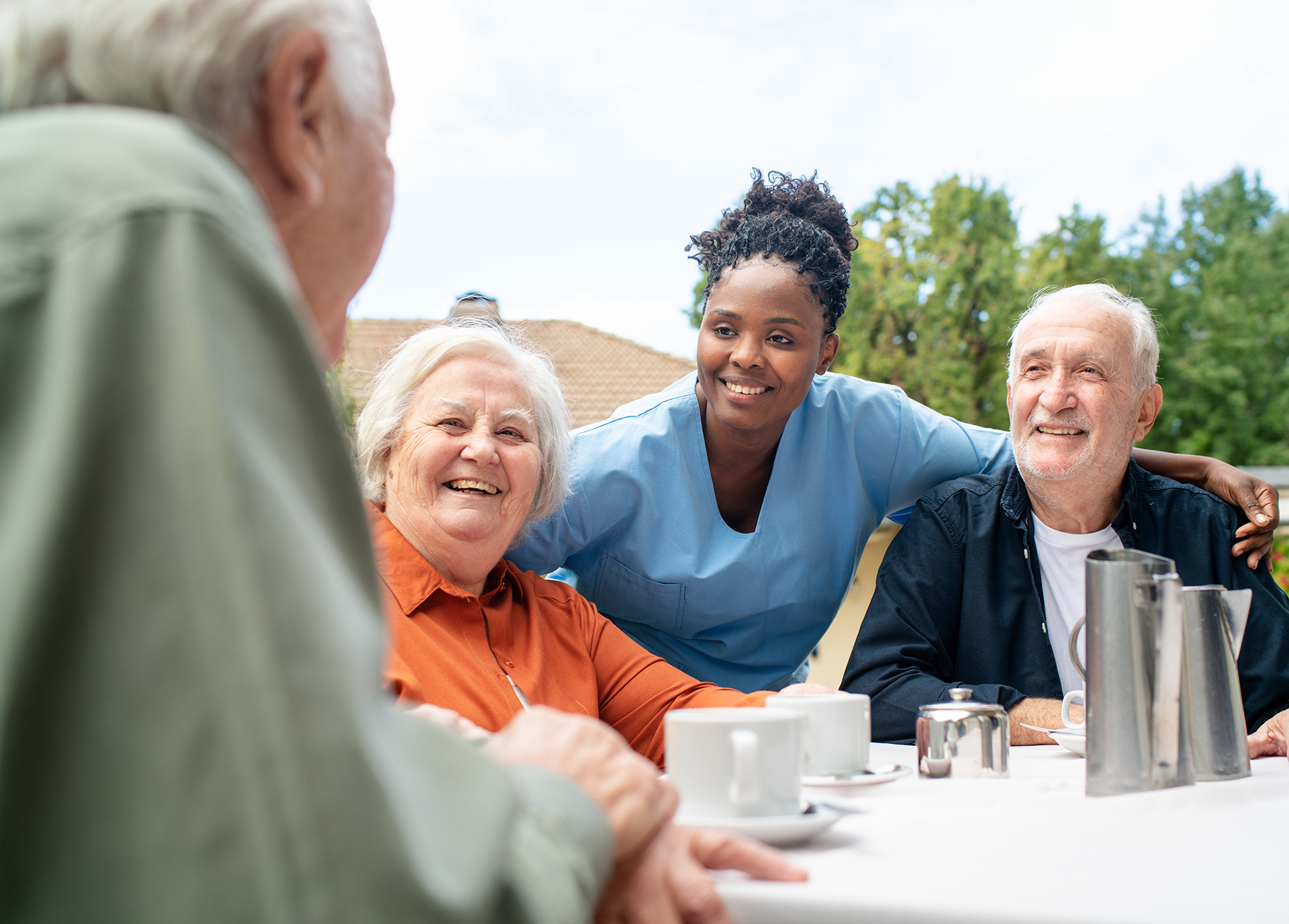 Nurse attends to socializing seniors on balcony at retirement home